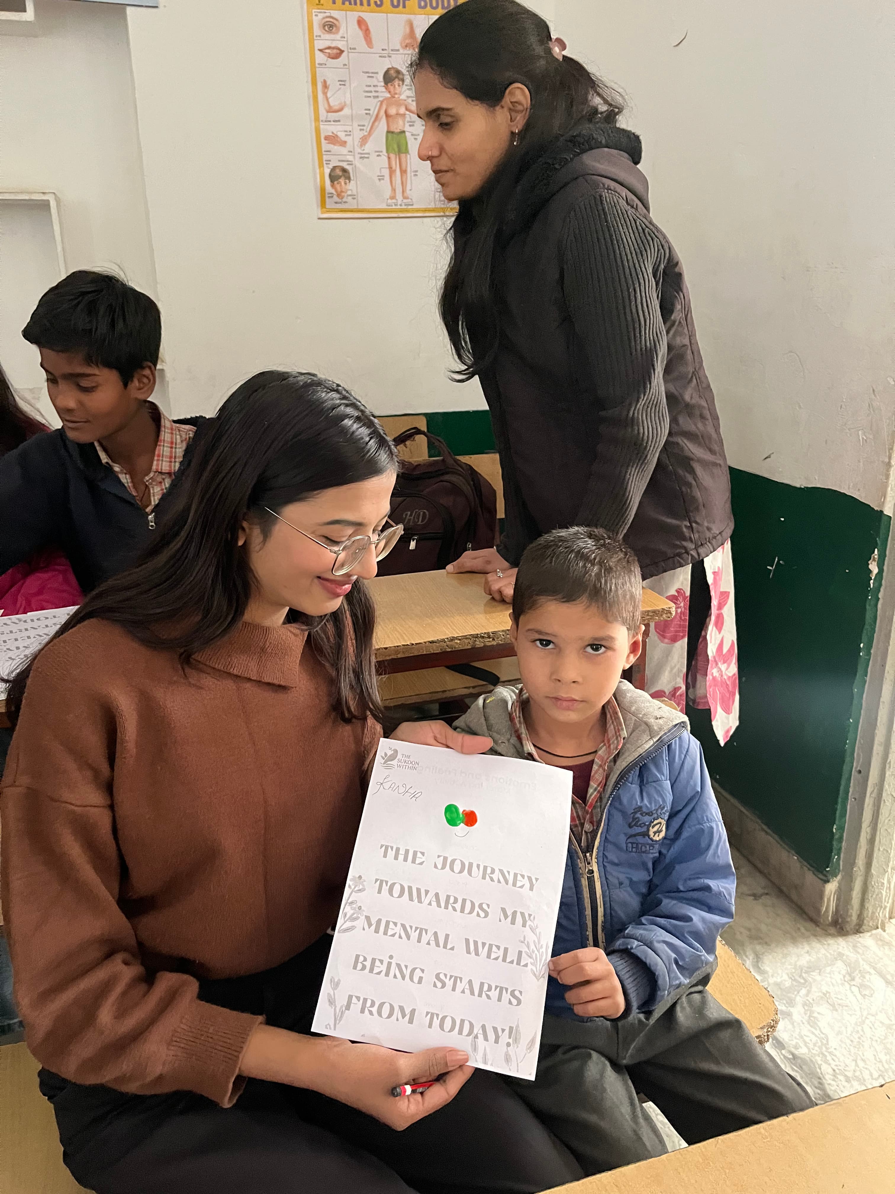 A volunteer and child holding a mental well-being activity sheet